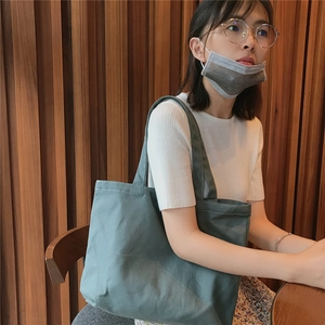 Détail du grand sac cabas en toile vert foncé sur modèle avec texture en coton épais