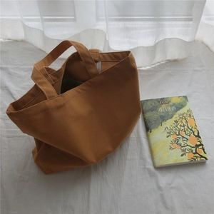 Gros plan détaillé d'un sac cabas minimaliste en toile marron sur un fond en tissu blanc