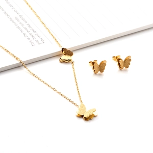 Détail macro d'un ensemble collier et boucles d'oreilles papillon dorés sur un carnet blanc