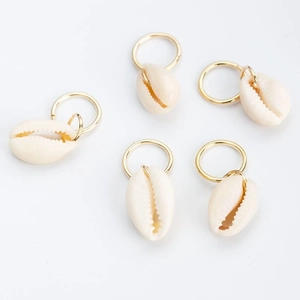 Detailed close-up of five golden hoop earrings with natural cream shell pendants