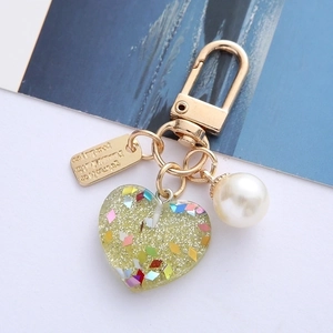 Detail of yellow resin heart keychain with glitter, pearl bead and Eternal Love tag