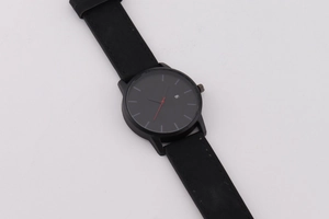 Gros plan d'un cadran de montre noir minimaliste avec trotteuse rouge et dateur
