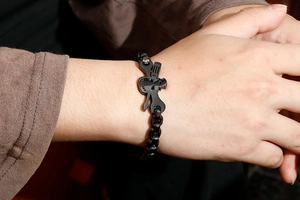 Detail of man wearing black punk bracelet with skull and guitar charms on wrist