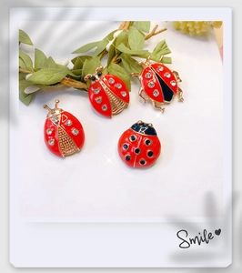 Detailed view of four red ladybug brooches with gold plating and sparkling rhinestones