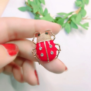 Close-up of a red ladybug beetle brooch with gold plating and sparkling crystals
