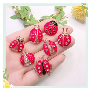 Detailed view of red ladybug brooches with gold trim and rhinestones held in a palm