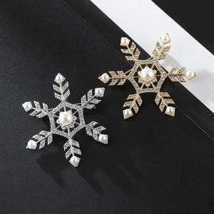 Detailed view of silver and gold snowflake brooches with shiny pearls and sparkling rhinestones