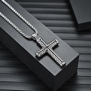 Vintage stainless steel cross necklace for men with textured pendant on black pedestal