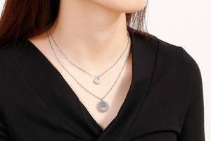 Detail of silver double-layer necklace with engraved heart pendant on a model