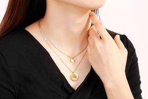 Detail of layered gold heart necklace with engraved pendant on a female model