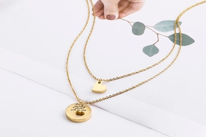 Macro view of gold double-layer necklace with engraved heart pendants and inspiring text