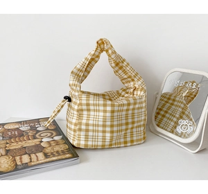 Détail du sac à nœud à carreaux jaunes et blancs avec perles décoratives sur le côté