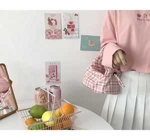 Détail du sac baguette à carreaux roses avec boucle noire réglable et texture toile