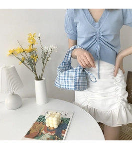 Gros plan d'un sac baguette à carreaux bleu et blanc sur un bureau minimaliste
