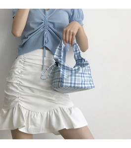 Détail du sac à main à carreaux bleu et blanc avec fermeture à cordon et poignées assorties