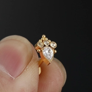 Gold G23 titanium labret stud with pear-shaped zircon and round stone on black background