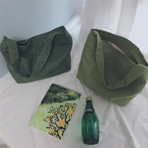 Top view of olive and moss green canvas tote bags with zipper details on white bedding