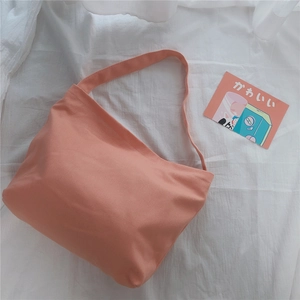 Detail of coral pink canvas shoulder bag with wide strap on soft white fabric background