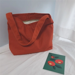 Detail view of red canvas tote bag with smooth zipper closure and reinforced wide handles