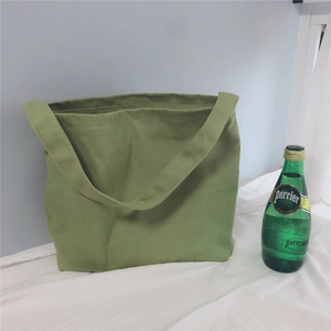 Detail of green canvas tote bag fabric texture with single wide shoulder strap