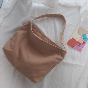 Close-up of khaki canvas tote bag showing weave texture and minimalist shoulder strap