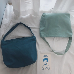 Overhead view of minimalist canvas shoulder bags in deep teal and pale mint green colors