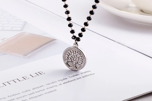 Macro detail of Tree of Life silver pendant with multifaceted black glass beads