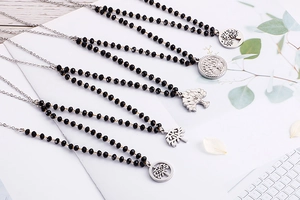 Detailed view of tree of life pendants with black beads on stainless steel necklaces