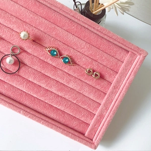 Close-up of pink velvet jewelry display tray with multiple slots for rings and studs