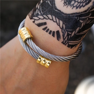 Macro-opname van zilveren gedraaide kabelarmband met twee gouden schuivers voor heren