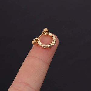 Macro view of gold U-shaped earring with zircon studs held to show mini size