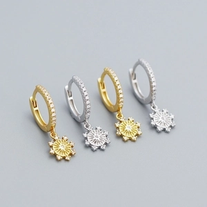 Detail of silver and gold snowflake earrings with micro-set cubic zirconia on grey background