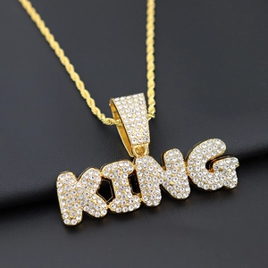 Macro shot of gold-plated KING pendant with sparkling crystals and twisted rope chain