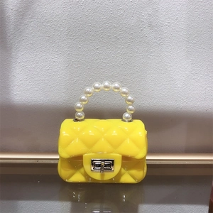 Detail of yellow mini PVC jelly bag with quilted pattern, pearl handle and golden clasp
