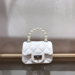 Detail of white quilted mini jelly bag featuring a glossy PVC finish and pearl handle