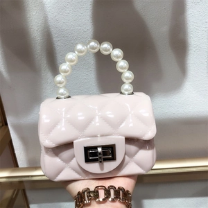 Detail of light pink mini jelly bag featuring quilted PVC pattern and faux pearl handle