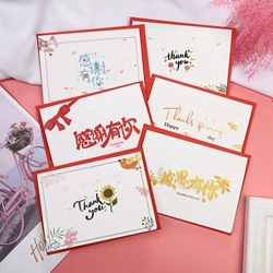 Assorted paper thank you cards with red borders and floral decor on pink background