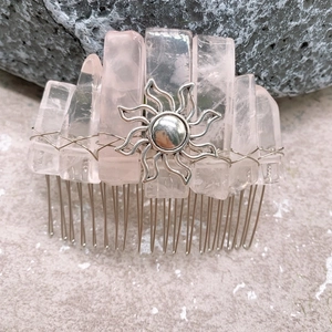 Detailed close-up of handmade pink crystal hair comb with a silver sun emblem on stone
