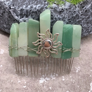 Detailed macro view of raw green crystal stones and sun charm on a silver hair comb