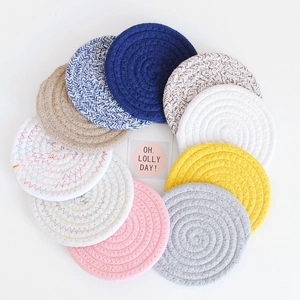 Flat lay of colorful braided cotton coasters in various shades for table protection