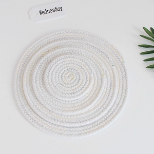 Close-up of white braided cotton coaster with yellow and grey stitching detail
