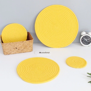 Detail of four yellow braided cotton heat-resistant coasters in various sizes