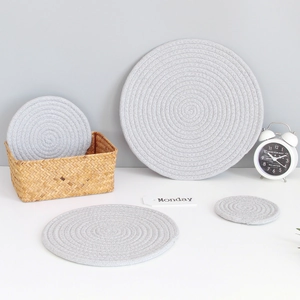 Set of four grey round woven cotton coasters in various sizes for dining table heat protection
