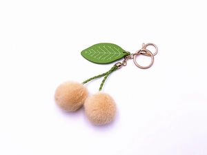 Detail of soft plush cherry keychain featuring double khaki faux fur balls and golden clasp