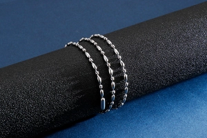 Close-up of silver stainless steel ball chain wrapped on a black display stand