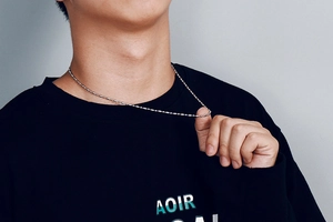 Close-up of a silver stainless steel ball chain necklace worn by a male model