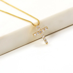 Macro view of gold cross necklace featuring sparkling white cubic zirconia inlay details