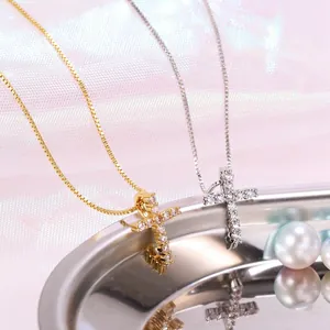 Close-up of gold and silver cross necklaces with white zircon inlays on a satin background