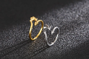Detail of adjustable devil wing and heart arrow rings in polished gold and silver finish