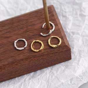 Macro shot of minimalist twisted S925 sterling silver ear cuffs in gold and silver